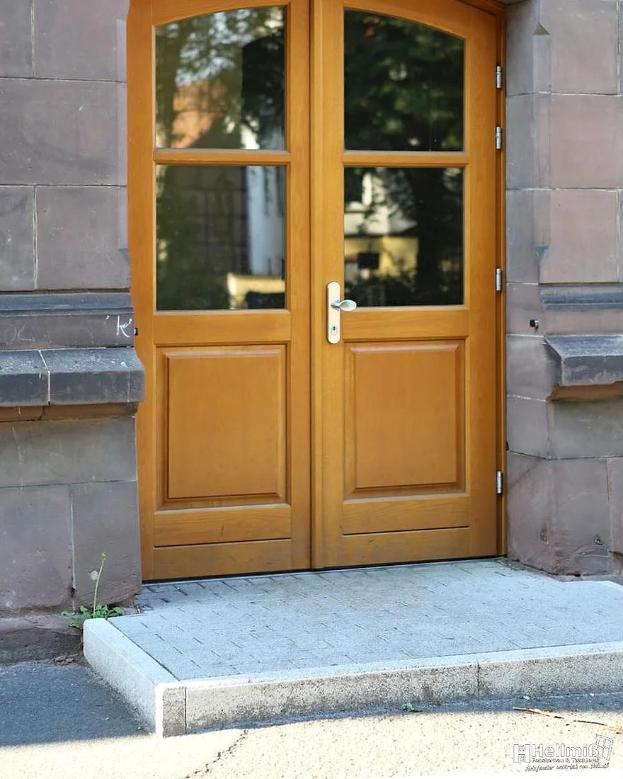 Von Hellmiß gefertigte Holztür mit Oberlicht in einem historischen Sandsteinportal